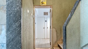 Ein Flur, der zu einer Toilette führt, mit einem Schild über der Tür.