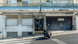 Ein Gebäude mit geschlossenem Garagentor, einem davor geparkten Motorrad und einem Balkon mit Metallgeländer.