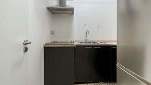Eine kompakte Küche mit einer Edelstahl-Dunstabzugshaube, einem Spülbecken und schwarzen Küchenschränken.