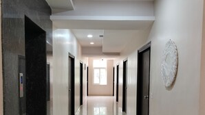 A long, well-lit hallway with a shiny tiled floor, black and white walls, and a large window at the end. - Yellow Sapphire Hotel Hitech City (Hyderabad)