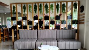 A modern living room with a grey sofa, a round white table with gold legs, and a wooden partition with hanging plants. - Yellow Sapphire Hotel Hitech City (Hyderabad)