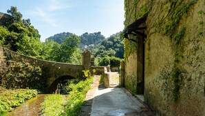 A stone bridge over a narrow path, leading to a rustic building with a stone wall and a wooden door. - Ravello Watermill Retreat – Your private oasis between lemon groves and the sea (Ravello)