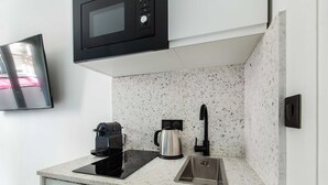 A kitchen with a microwave, coffee maker, and sink. - Cosy Apartment - 2P - Exhibitions Park (Paris)