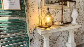 Une pièce au style rétro, avec un banc en bois, un miroir fixé au mur et une table avec une lampe.