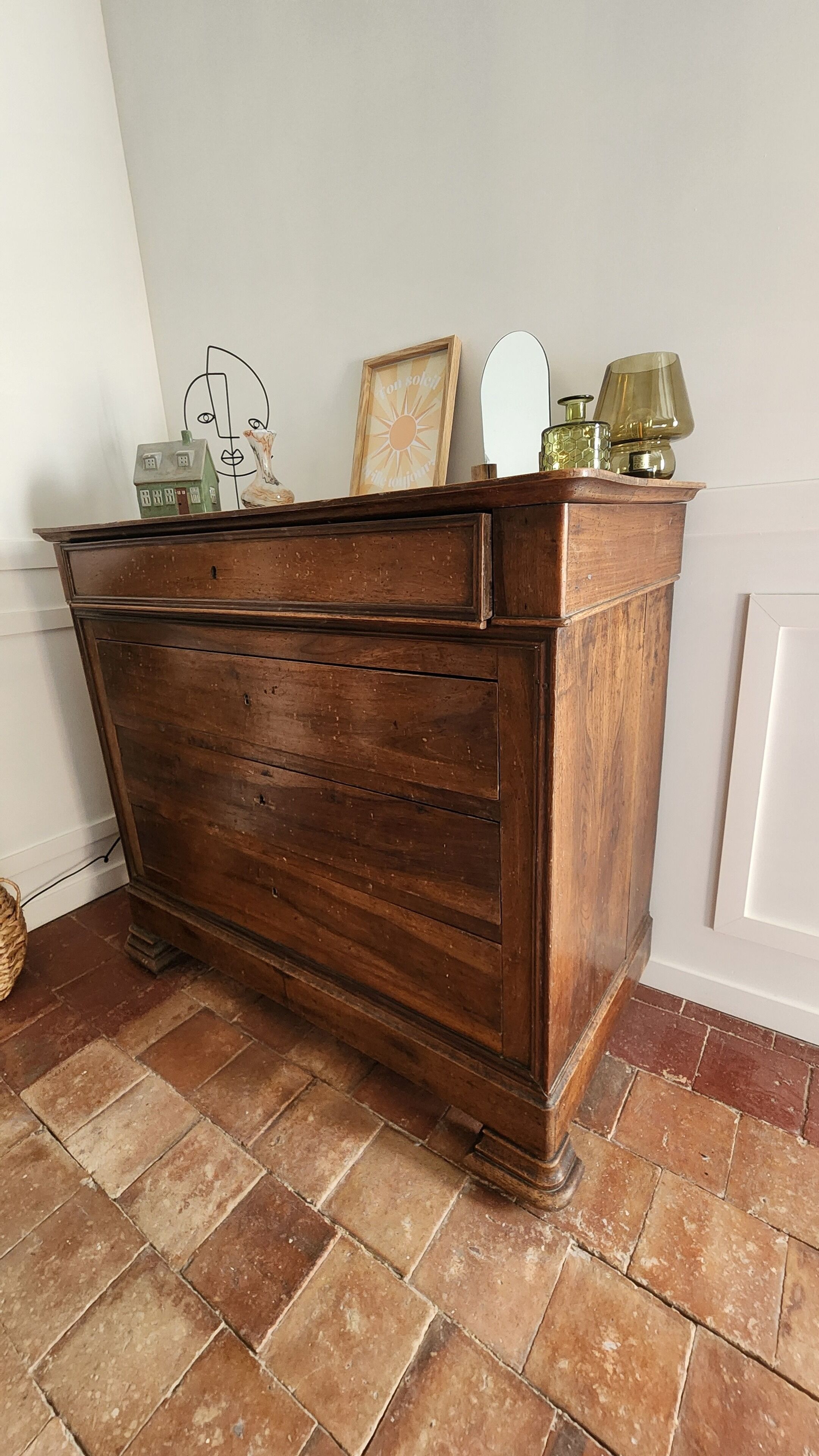 A wooden dresser with multiple drawers, a mirror, and decorative items on top.