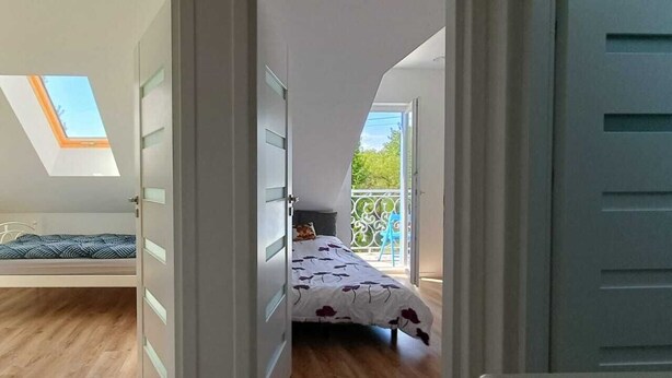 Ein Schlafzimmer mit Dachfenster, einem Balkon und einem Bett mit einem gemusterten Überwurf.