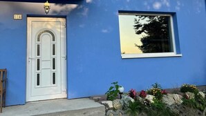 Ein zweistöckiges Gebäude mit blauer Fassade, einer weißen Tür und einem kleinen Fenster.