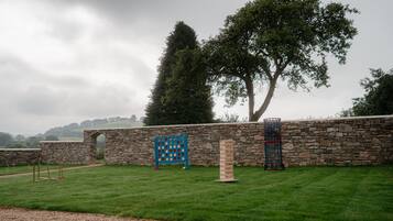 Un mur de pierres avec une clôture en bois, une zone herbeuse et un arbre.
