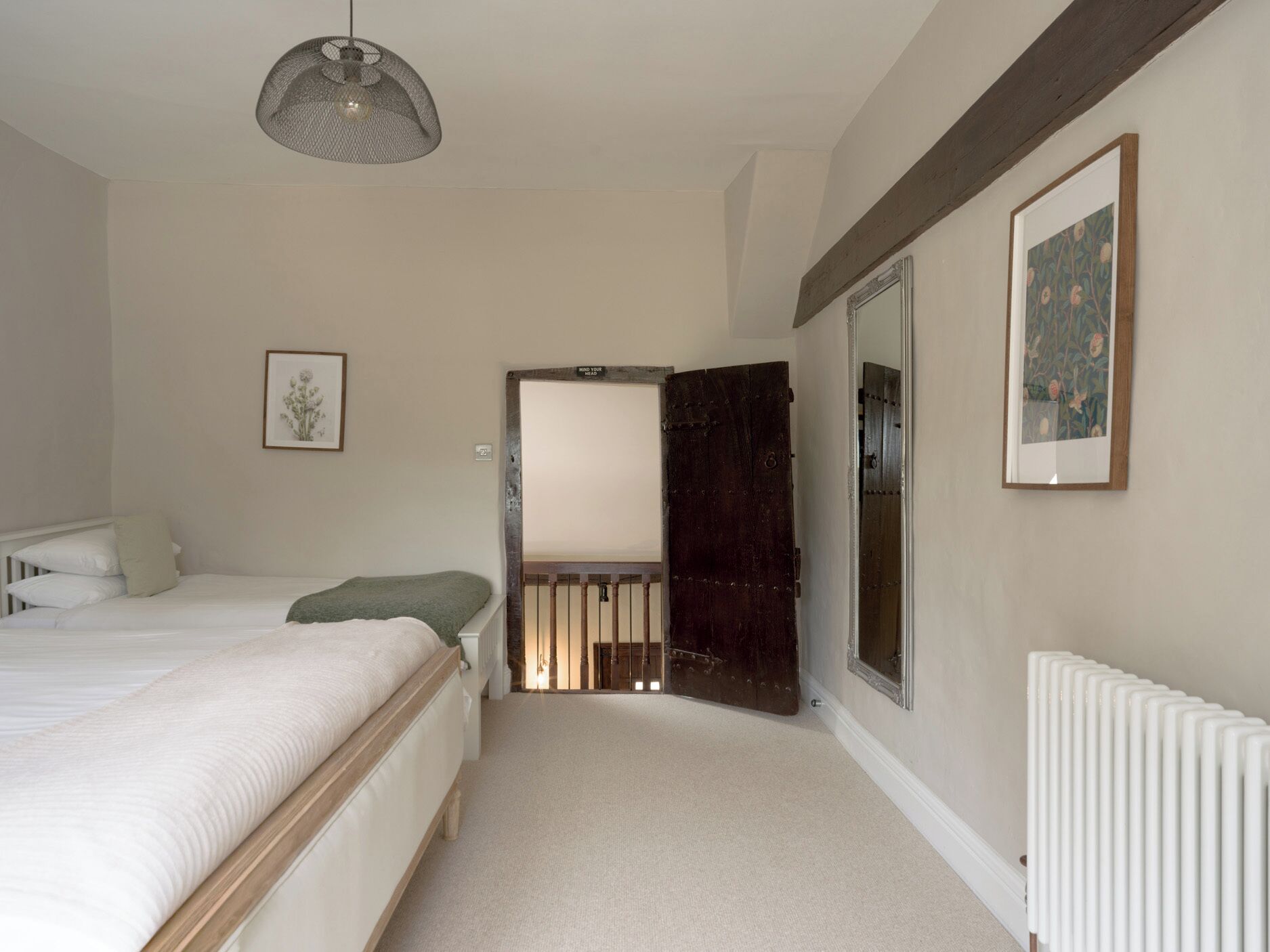 A bedroom with a bed, a radiator, a door, and a framed picture on the wall.