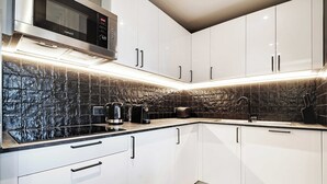 A modern kitchen with white cabinets, a black backsplash, and stainless steel appliances. - Modern Apartment - 2br/8p - Near Opera Garnier (Paris)