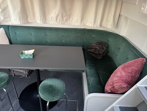 En grøn sofa med pude, et lille bord og to grønne stole.