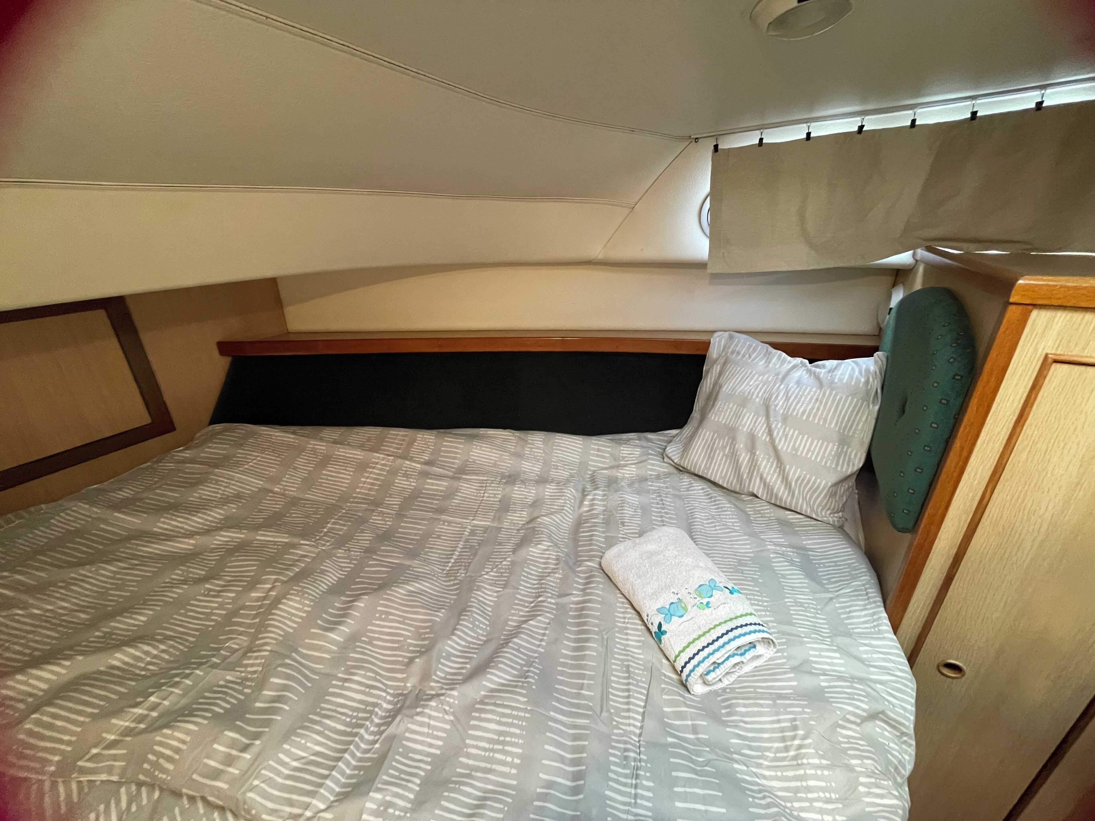 Ein kleines Zimmer mit Bett, Kopfteil und einer kleinen Garderobe.