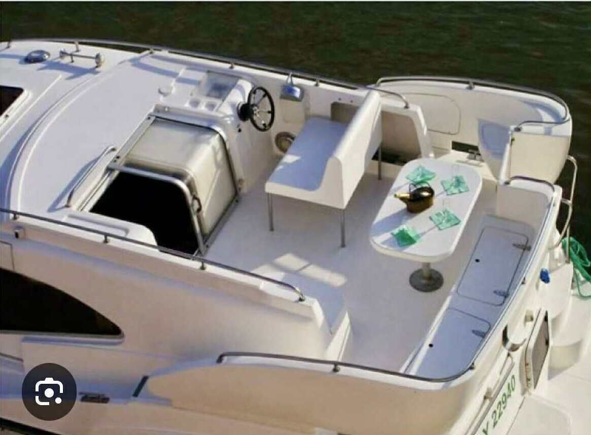 A boat with a covered seating area, a steering wheel, and a table with green placemats.