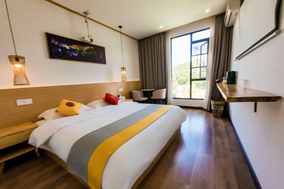 Una habitación de hotel con una cama grande, un escritorio, una silla, un televisor y una ventana con cortinas.
