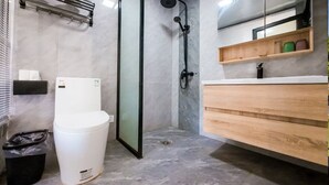 Un baño moderno con ducha de vidrio, inodoro blanco, tocador de madera y espejo sobre el tocador.