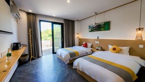 Habitación de hotel con dos camas, un escritorio de madera, una ventana con cortinas y una obra de arte colgada en la pared.