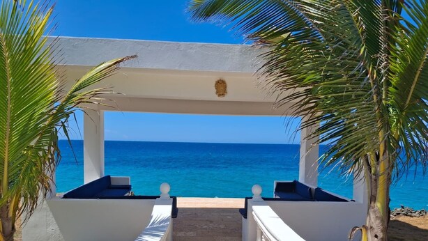 A covered outdoor seating area with a view of the ocean.