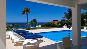 A poolside area with lounge chairs and a view of the ocean.