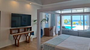 A bedroom with a large bed, a TV, and a view of the ocean.