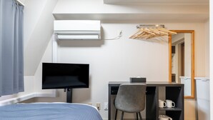 A modern hotel room with a bed, a desk with a chair, a flat-screen TV, a small shelf with mugs, and a mirror. - Sleep Inn Gotanda (Tokyo)