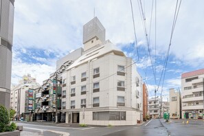A multi-story hotel with a modern design, featuring a prominent corner entrance and a rooftop terrace. - Sleep Inn Gotanda (Tokyo)