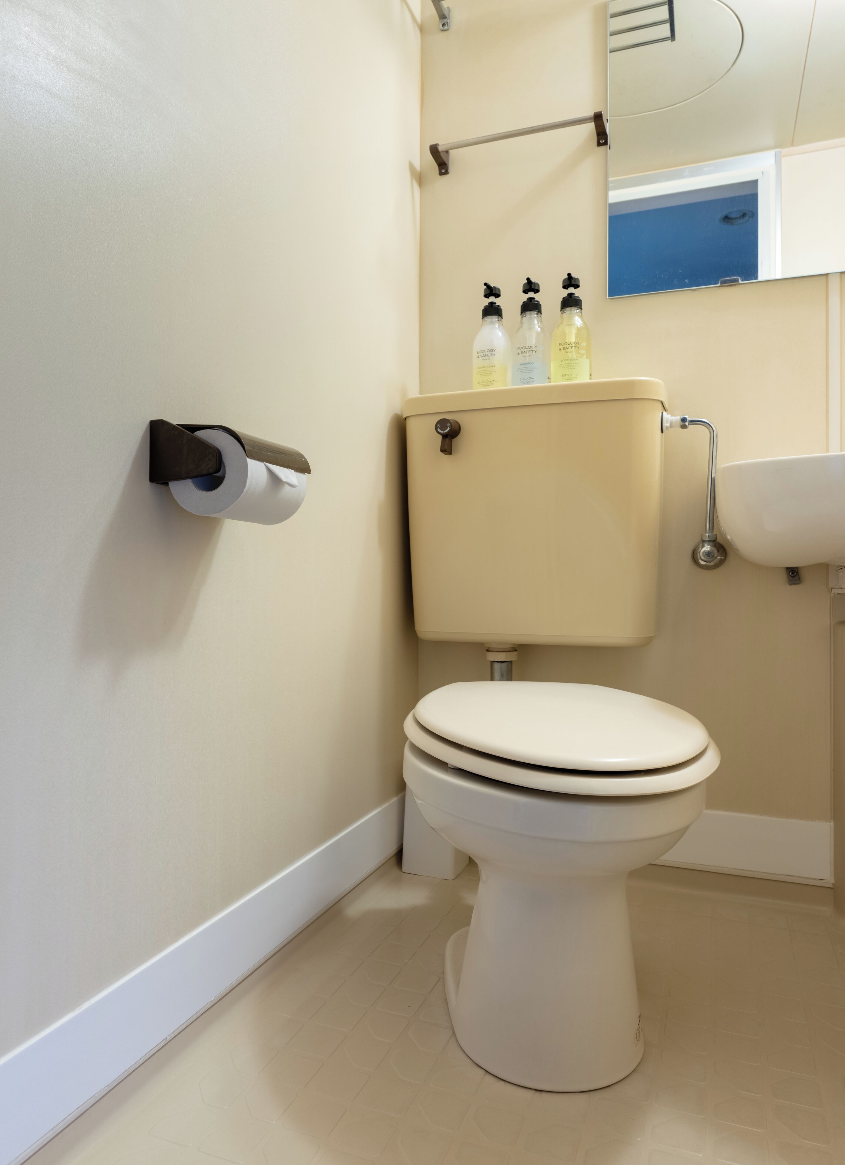 A bathroom with a toilet, a toilet paper holder, a hand dryer, and a sink.