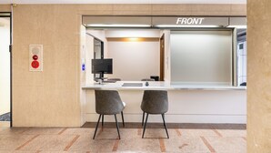 A reception desk with two grey chairs, a computer monitor, and a sign reading "FRONT". - Sleep Inn Gotanda (Tokyo)
