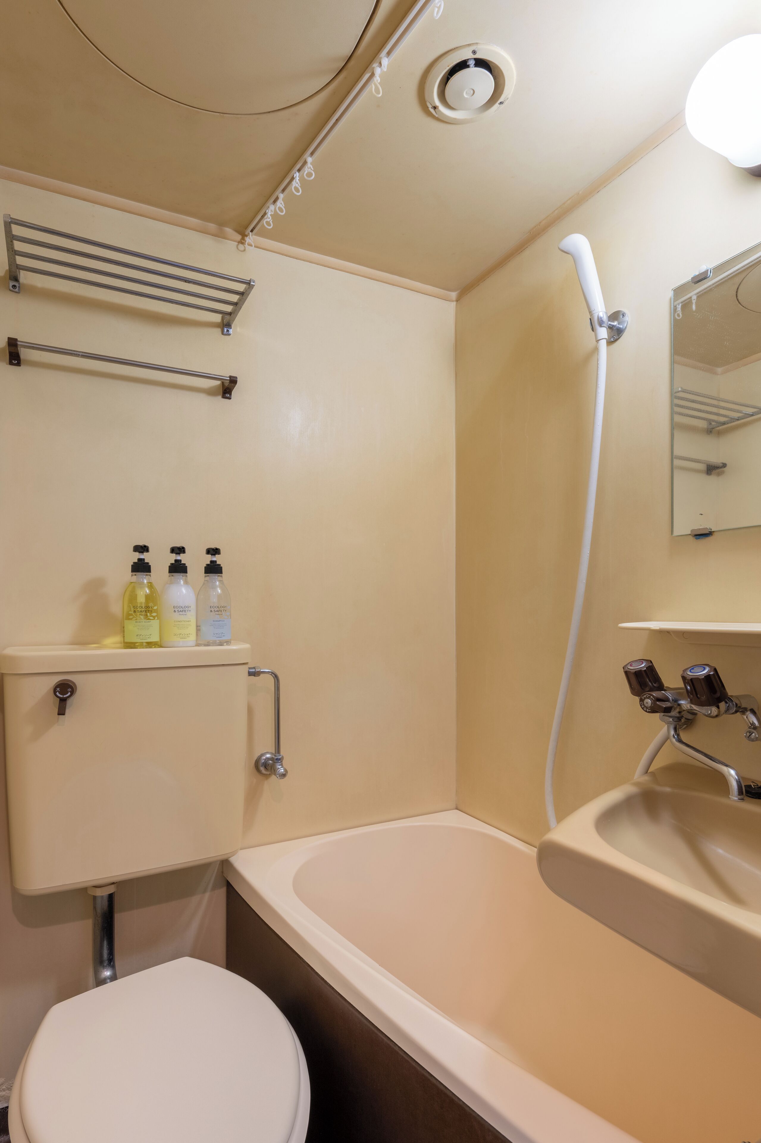 A bathroom with a bathtub, toilet, shower, and a shelf with toiletries.