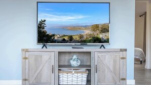 A TV mounted on a wooden cabinet with a scenic view of a coastline. - Coastal Charm - Oceanview Stay in Pacifica Near SF (Pacifica)