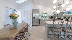 A modern kitchen with a dining area, featuring a large island, stainless steel appliances, and pendant lighting. - Coastal Charm - Oceanview Stay in Pacifica Near SF (Pacifica)