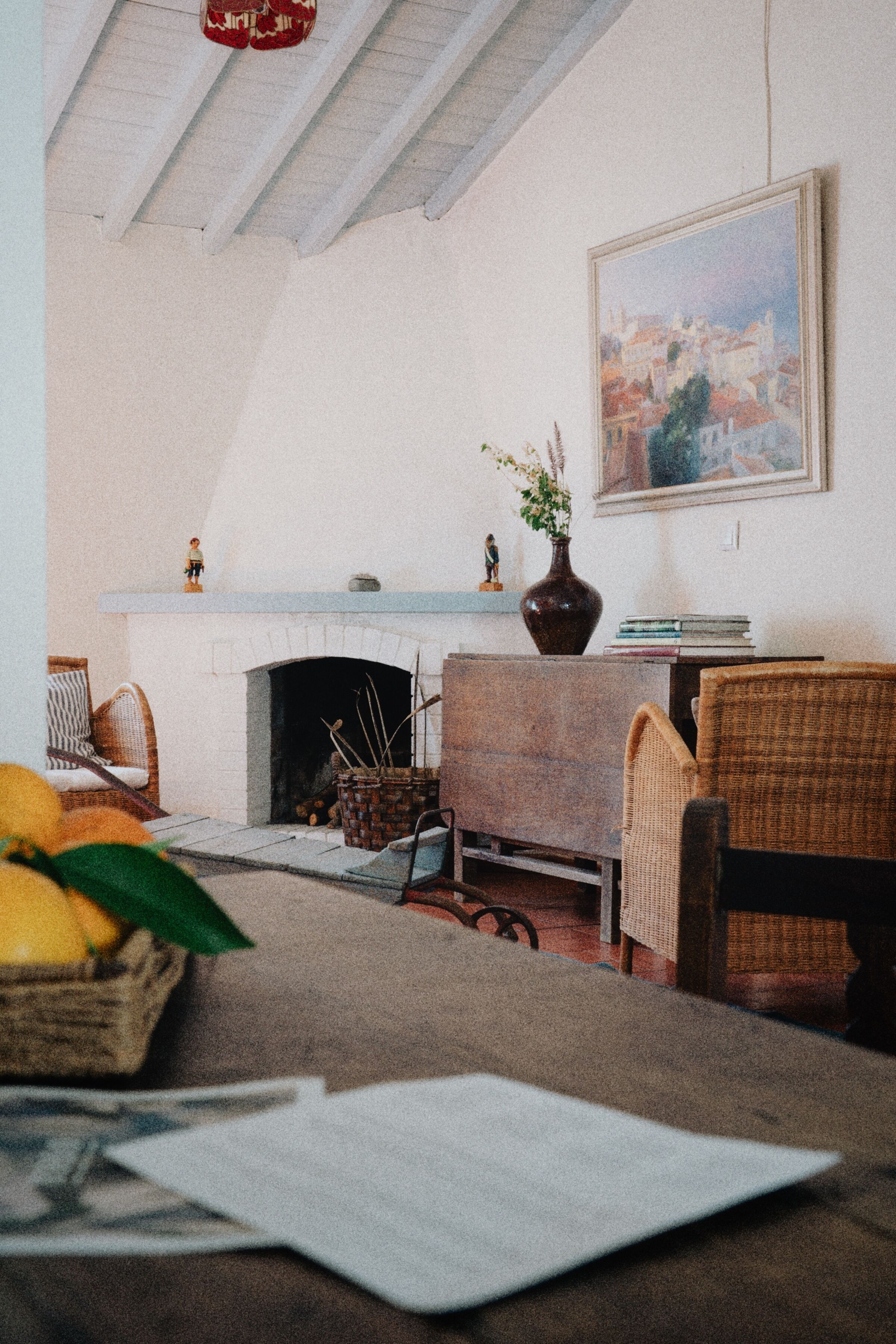 Ein gemütliches Wohnzimmer mit Kamin, Korbmöbeln und einem Bild an der Wand.