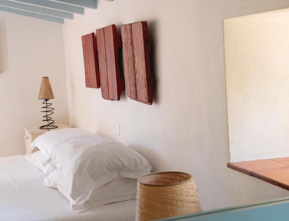 A bedroom with a bed, a lamp, and a wall-mounted wooden panel.