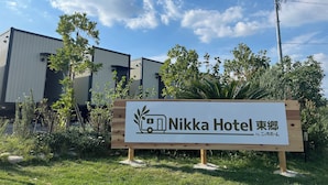 A sign for Nikka Hotel with a modern building in the background. - NikkaHotel togo (Togo)