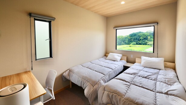 A bedroom with two beds, a desk, and a chair. - NikkaHotel togo (Togo)