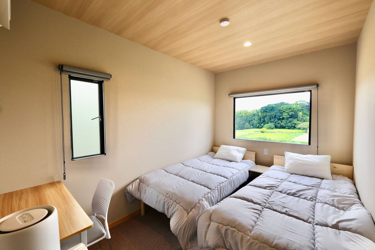 Quarto com duas camas, uma escrivaninha e uma cadeira.