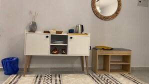 A room with a white cabinet, a mirror, a small wooden table, and a patterned rug. - Sunny Haven 1BR Apartment: A Luxurious Retreat near Cairo Airport (Cairo Governorate)