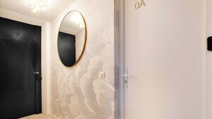Ett hotellrum med en svart dörr, en rund spegel och en vägg med ett diskret mönster.