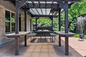 Un patio al aire libre con pérgola, muros de piedra y una parrilla.