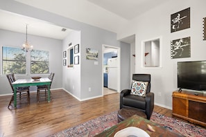 A modern living room with a dining area, a TV, and artwork on the walls.