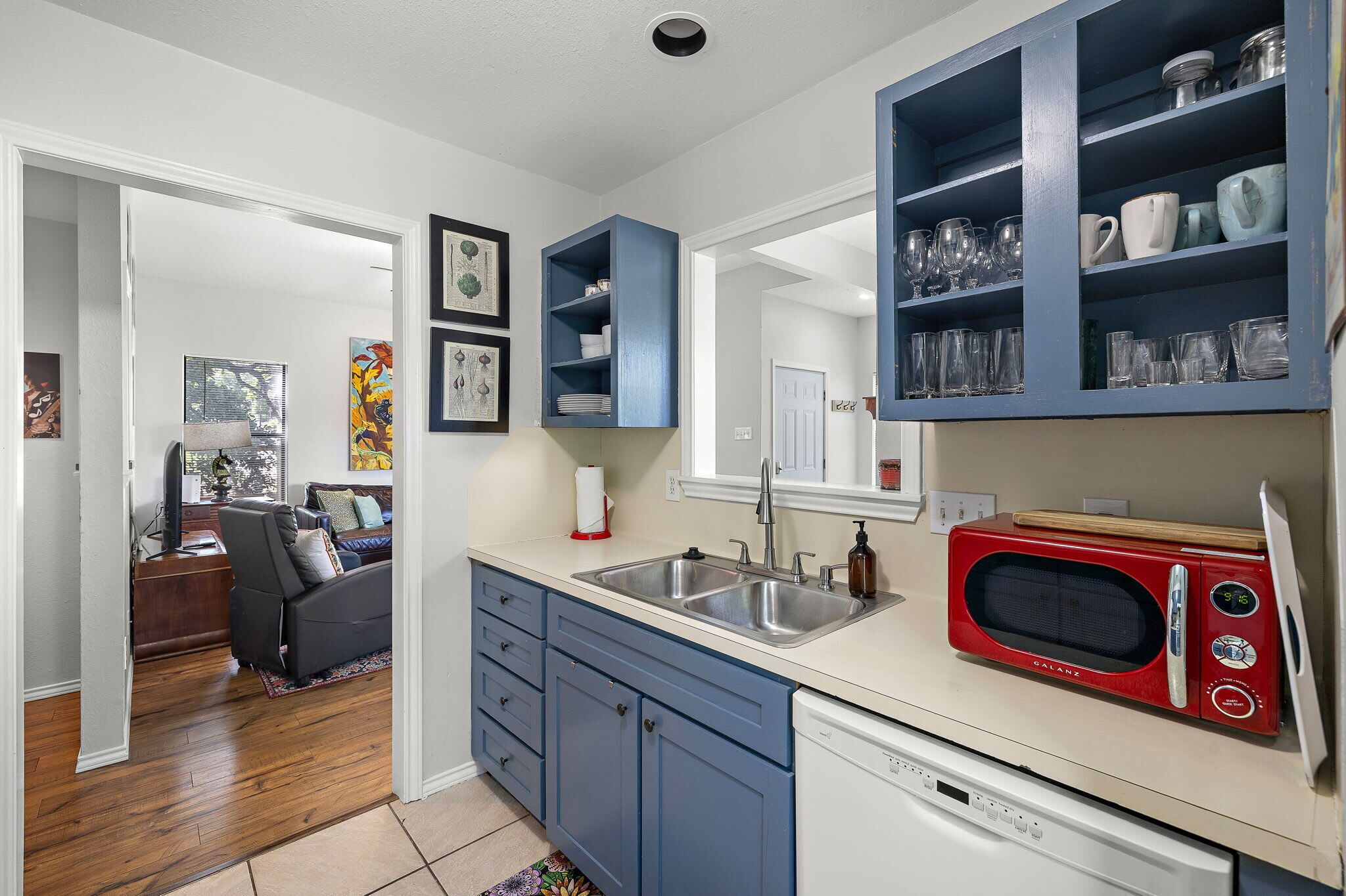 Een moderne keuken met blauwe kastjes, een rode magnetron en een inbouwgootsteen.
