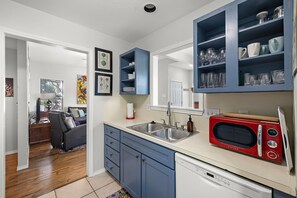 A modern kitchen with blue cabinets, a red microwave, and a built-in sink.