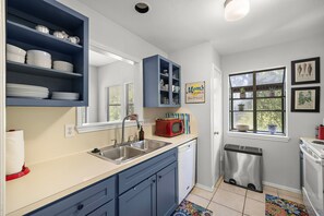 Cucina con mobili blu, un forno a microonde rosso e una lavastoviglie.