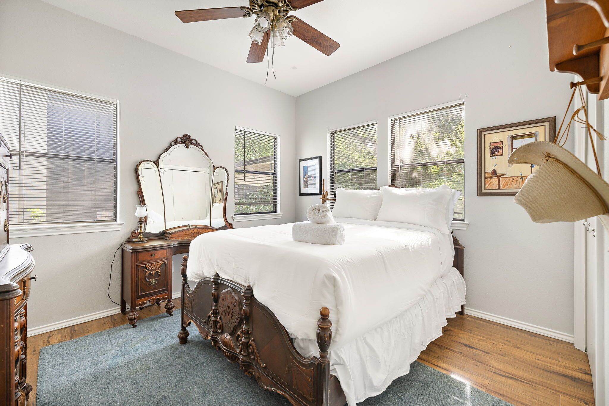 A bedroom with a wooden bed, a ceiling fan, and a large window with blinds.