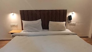 A large bed with a headboard, two bedside tables, and a wall-mounted telephone.