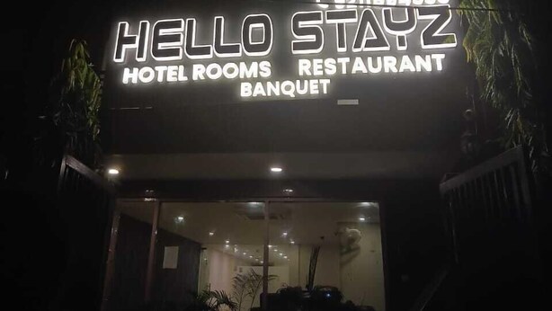 A building with a sign that reads "HELLO STAYZ HOTEL ROOMS RESTAURANT BANQUET."