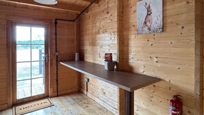A wooden interior with a wooden door, a welcome mat, a bench, a wall-mounted picture, and a fire extinguisher.