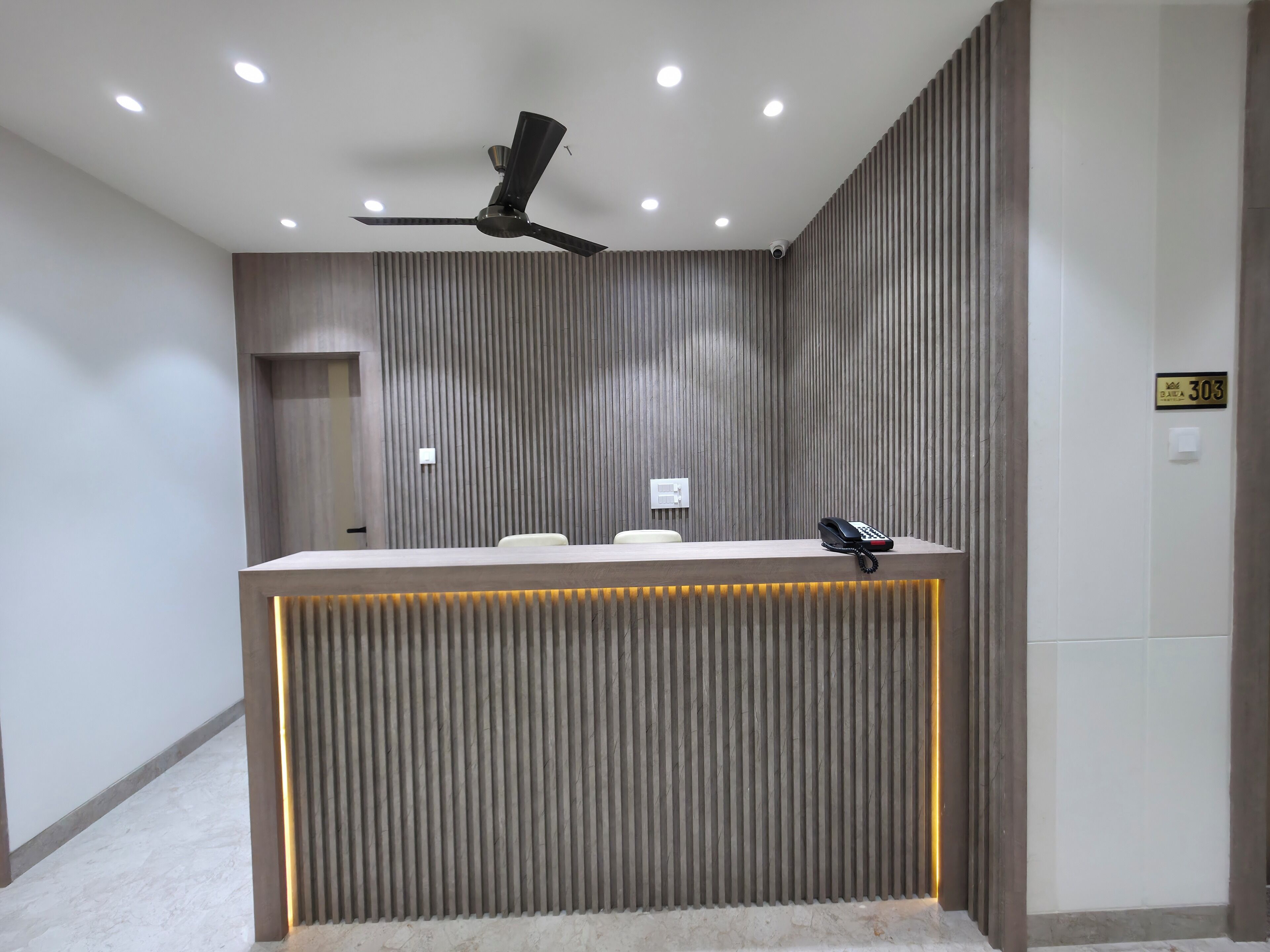 A reception desk with a modern design, a ceiling fan, and recessed lighting.