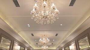 A grand hallway with a large crystal chandelier, mirrored doors, and recessed ceiling lighting. - Bawa Hotel (Kanpur)