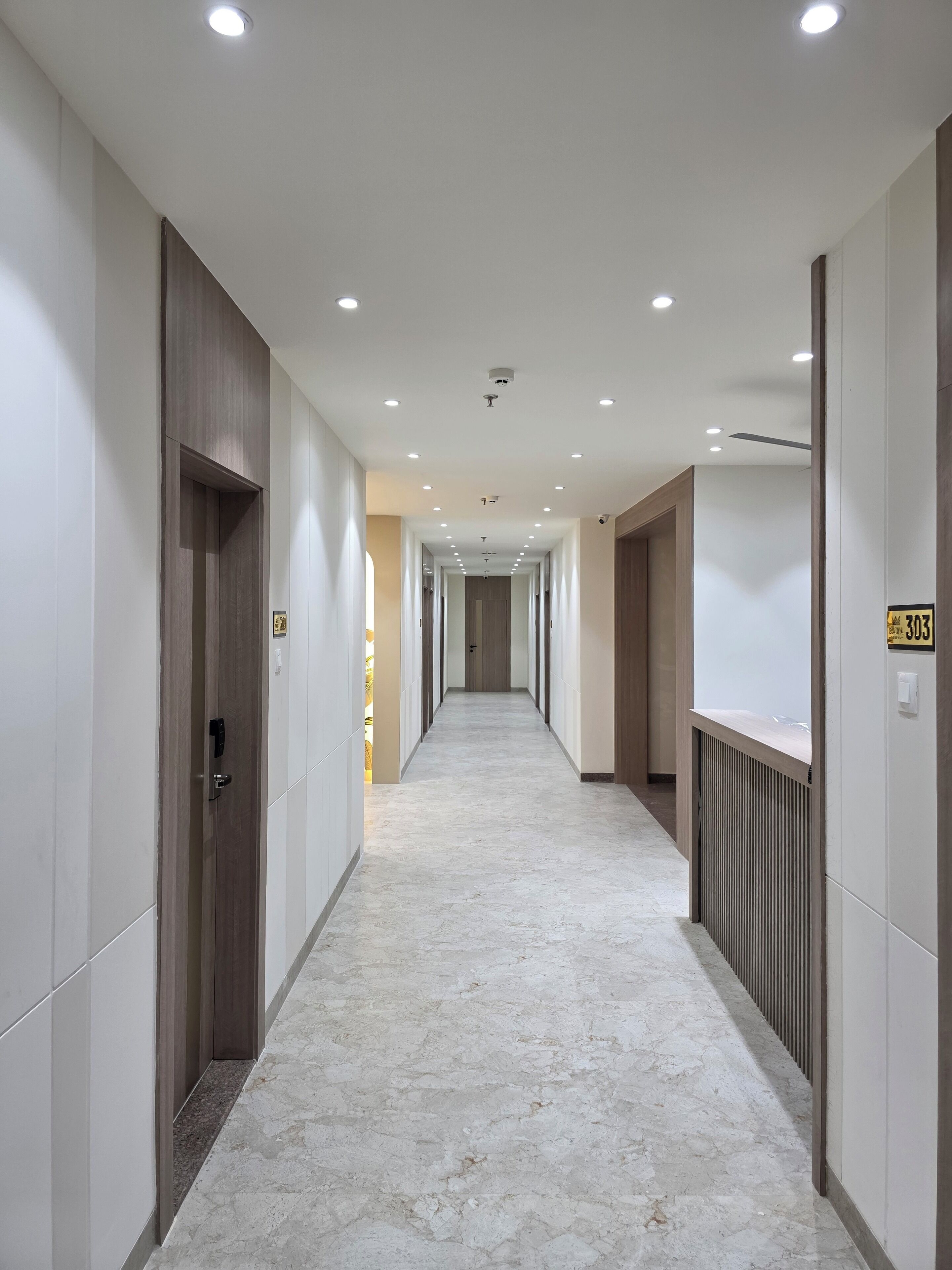 A long, narrow hallway with white walls and a marble floor.