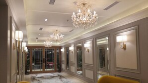 A spacious lobby with marble flooring, two yellow sofas, and ornate chandeliers. - Bawa Hotel (Kanpur)